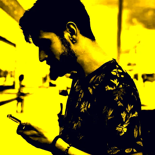 Dhiego looking down at his phone, yellow duotone portrait
